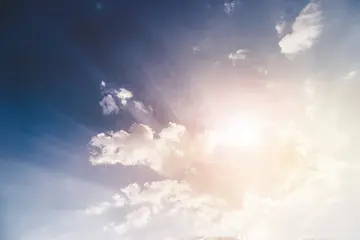 Bright sunlight shining through clouds in a blue sky